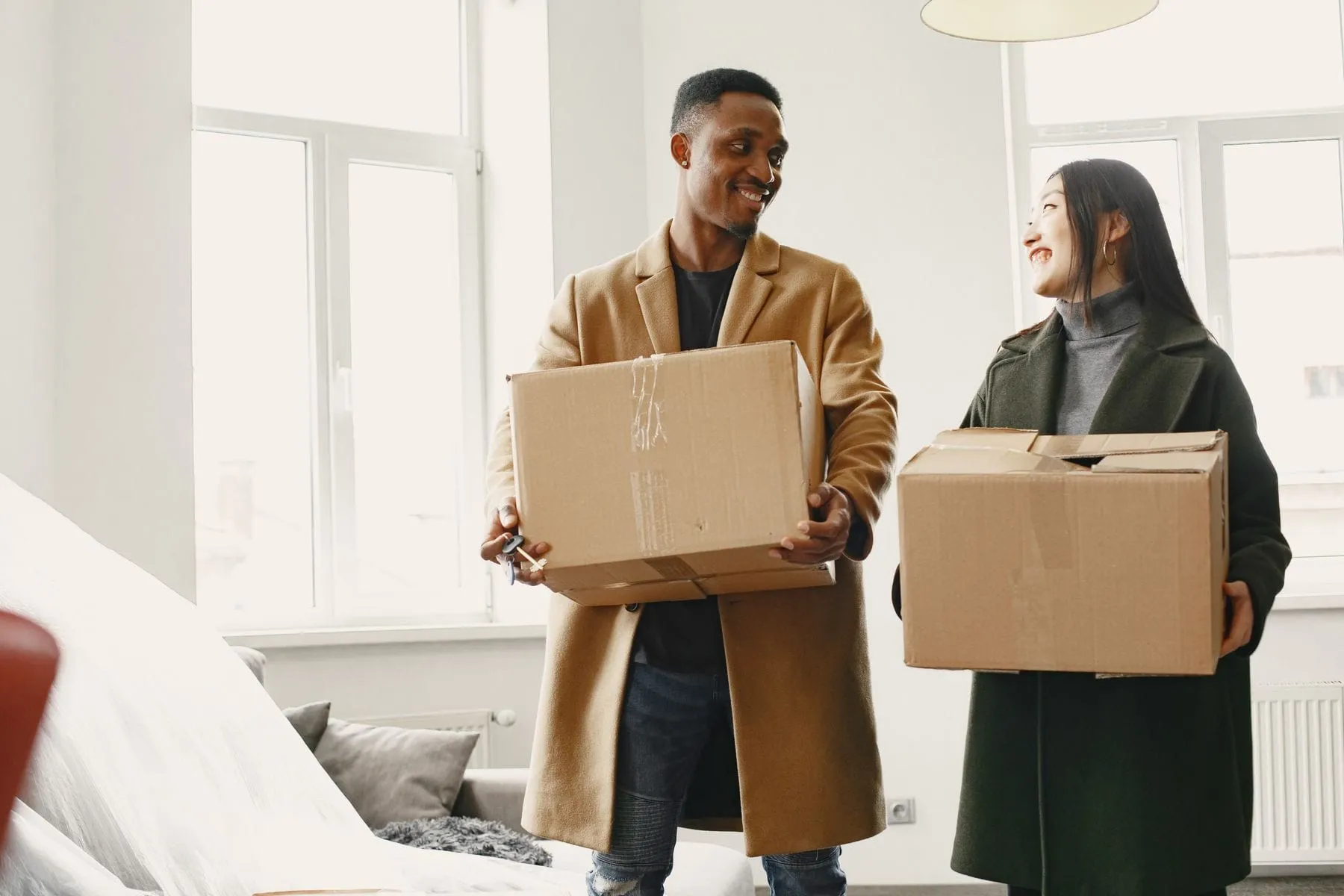 Couple carrying moving boxes into their new apartment