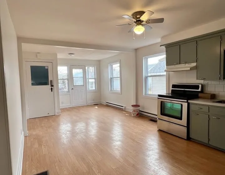 Open living and dining area with hardwood floors leading to the kitchen, 8th Street East unit